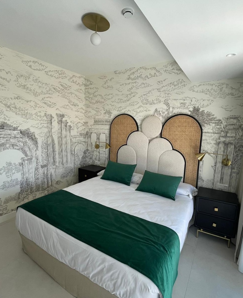 Dormitorio en suite de hotel con papel pintado decorativo y cabecero tapizado en proyecto de interiorismo en Tenerife